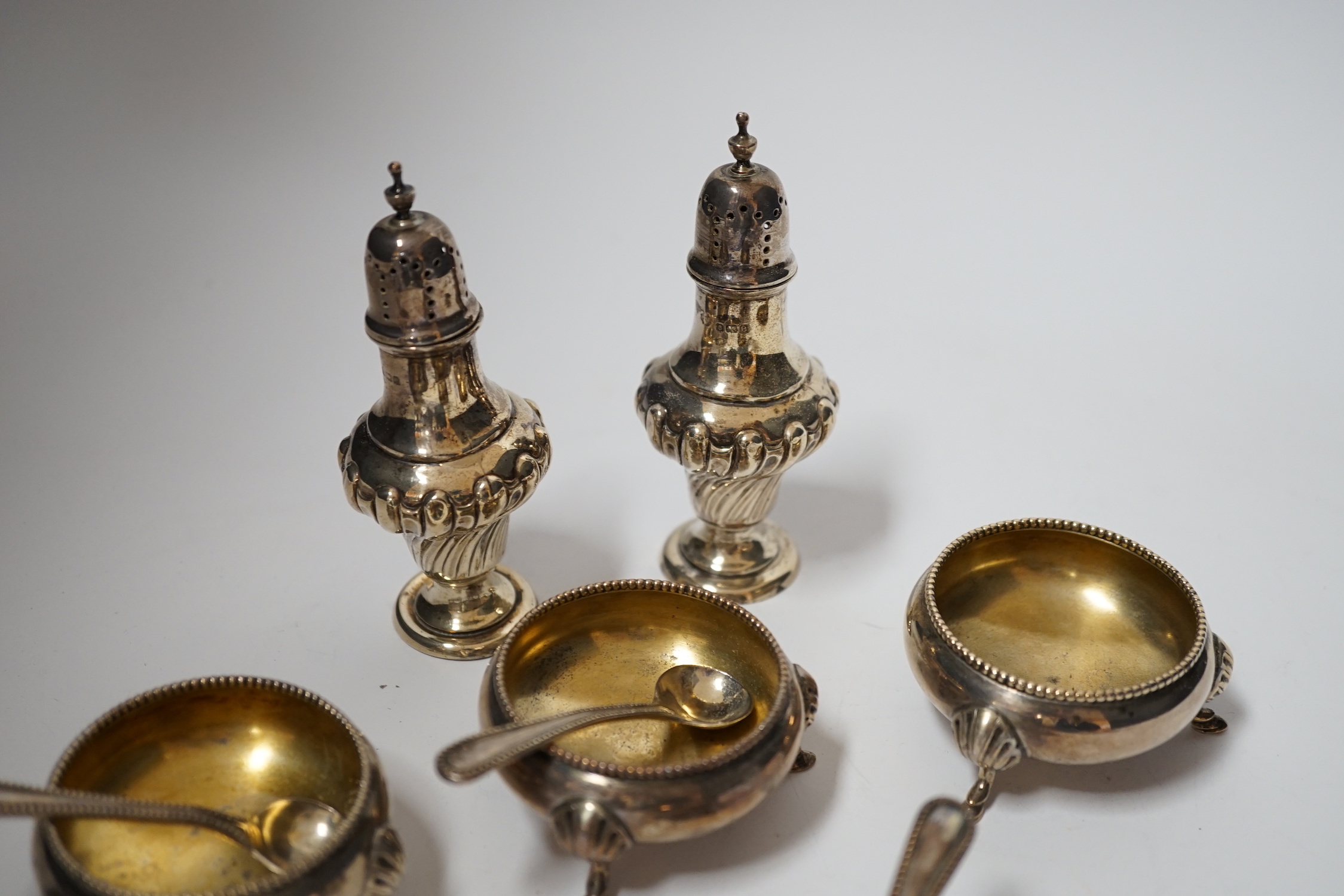A set of four late Victorian silver bun salts by Hukin & Heath, with four matched spoons and a pair of silver pepperettes